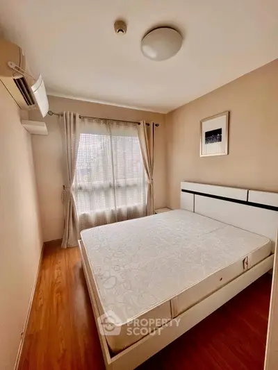 Cozy bedroom with large window and modern furnishings, perfect for relaxation.