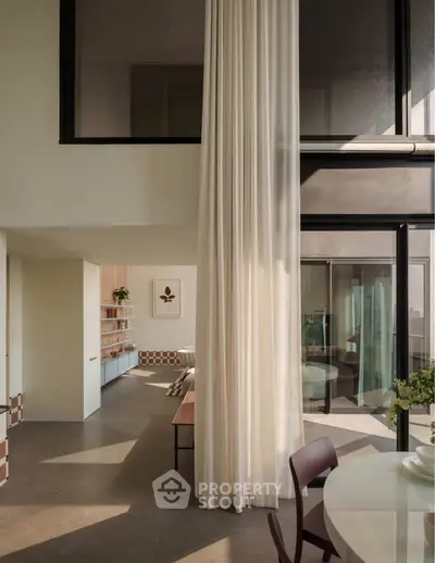 Stunning modern living room with high ceilings and elegant decor, featuring floor-to-ceiling windows and chic furnishings.