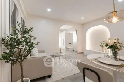 Elegant living room with modern decor, featuring a cozy sofa, stylish lighting, and a dining area.