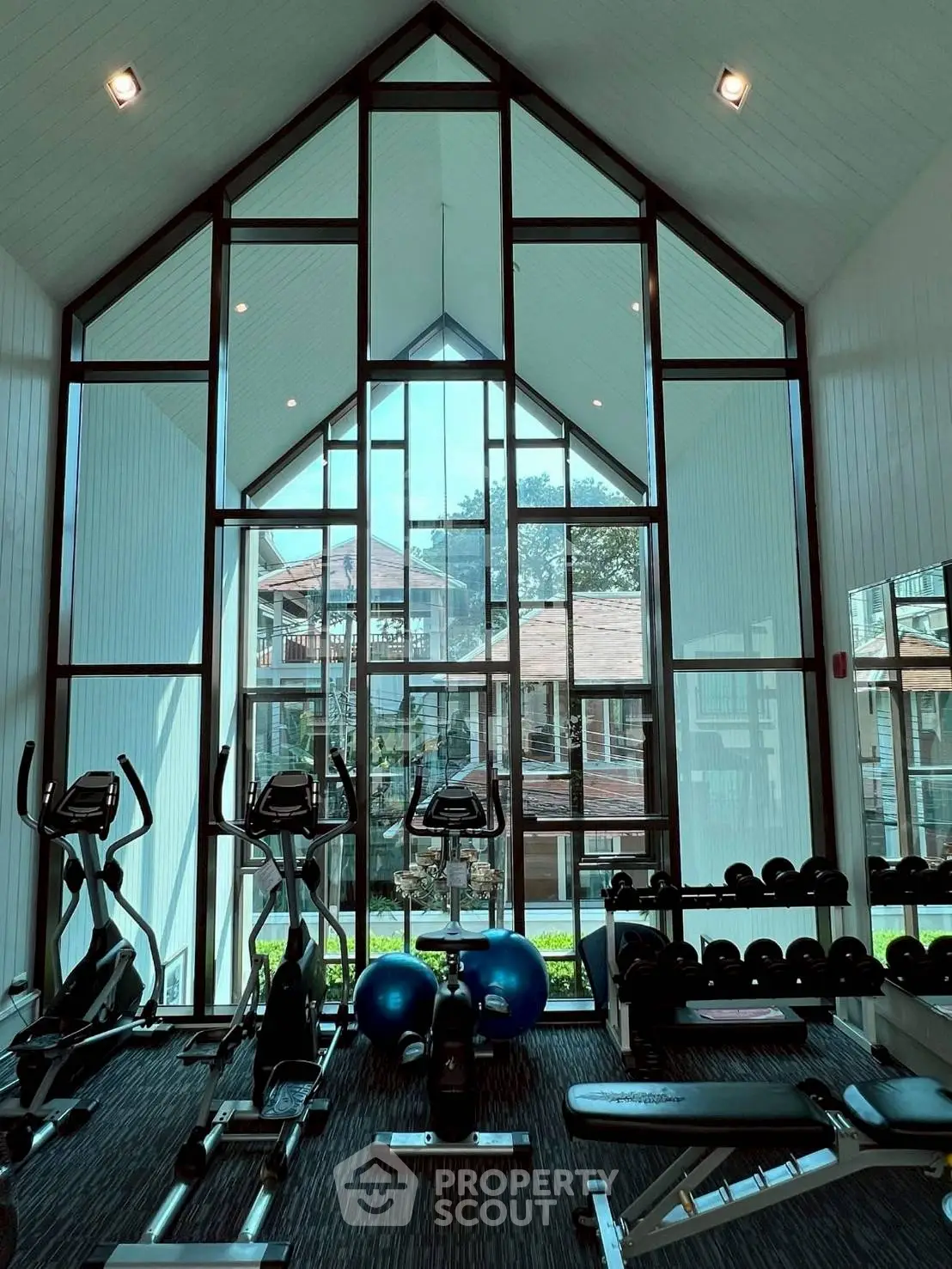 Modern gym with high ceilings and large windows in luxury residential building.