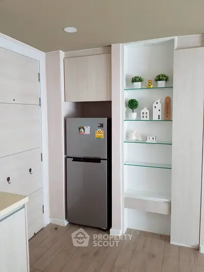 Modern kitchen with sleek fridge and stylish shelving in a compact layout
