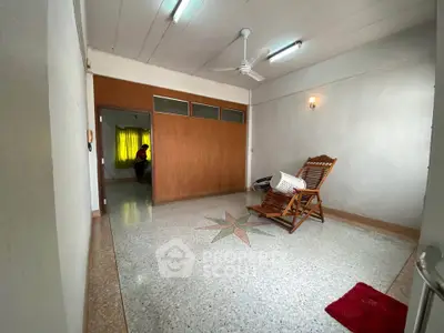 Spacious living room with unique floor design and wooden chair, ideal for relaxation.
