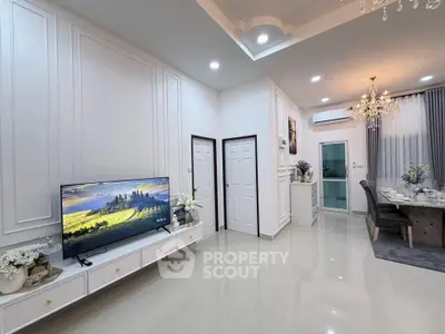 Elegant living room with modern decor and dining area, featuring a flat-screen TV and chandelier lighting.