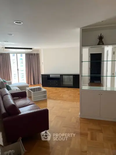 Spacious living room with parquet flooring and modern furniture in a bright apartment.