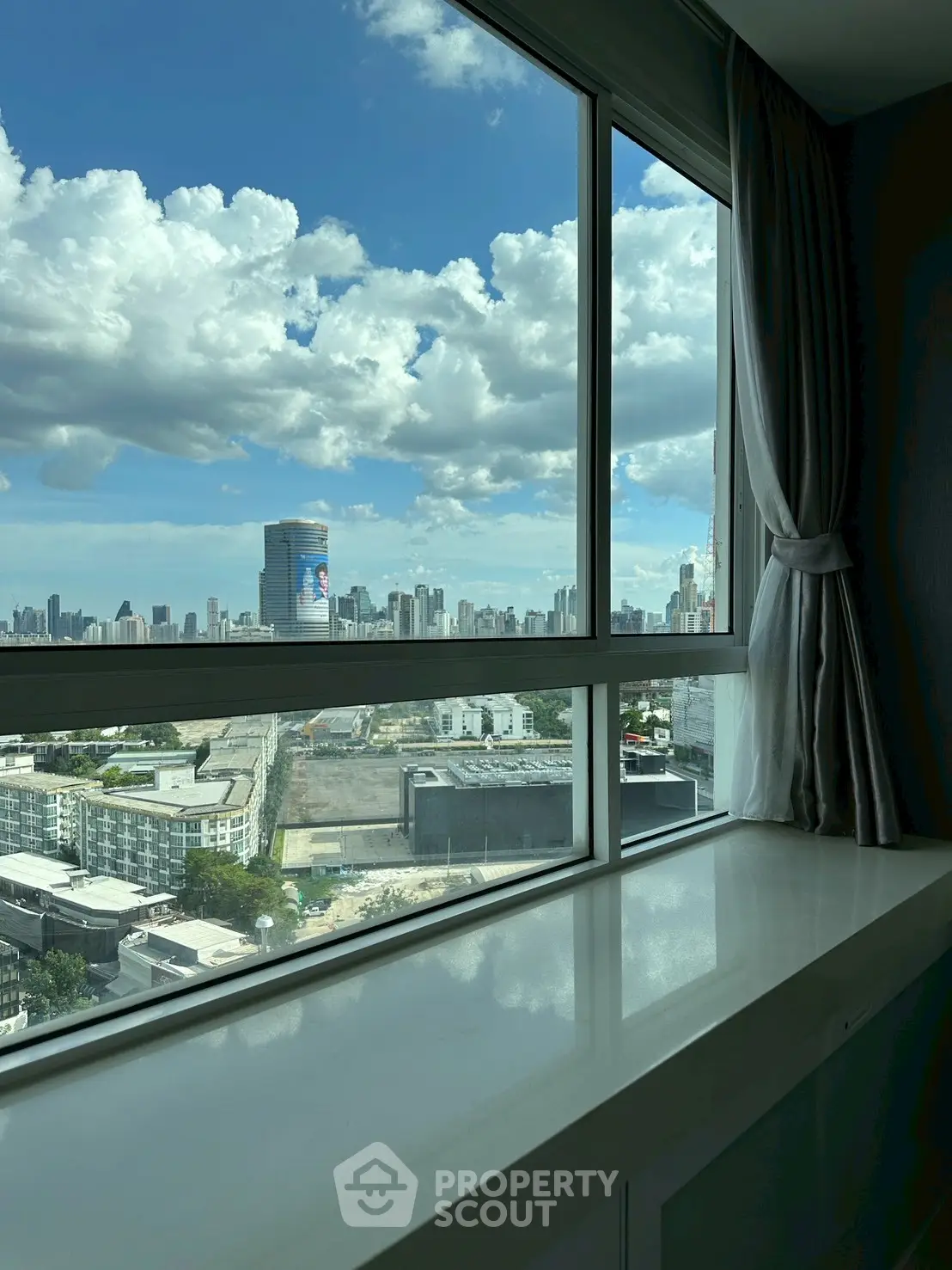 Stunning cityscape view from a modern high-rise apartment window with clear blue skies.