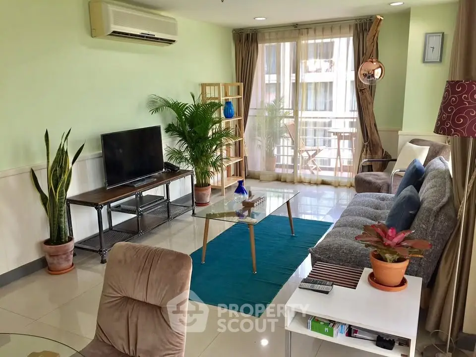 Spacious living room with modern decor and balcony access, featuring a cozy seating area and natural light.