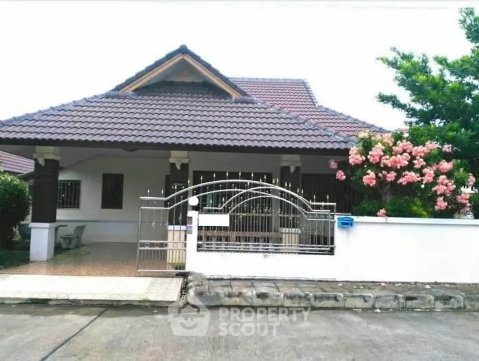 Charming single-story house with tiled roof and blooming garden in serene neighborhood.