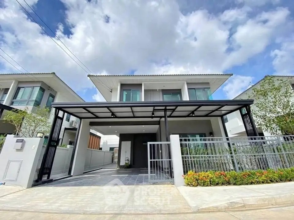 Modern two-story house with sleek design and spacious driveway under a clear blue sky.