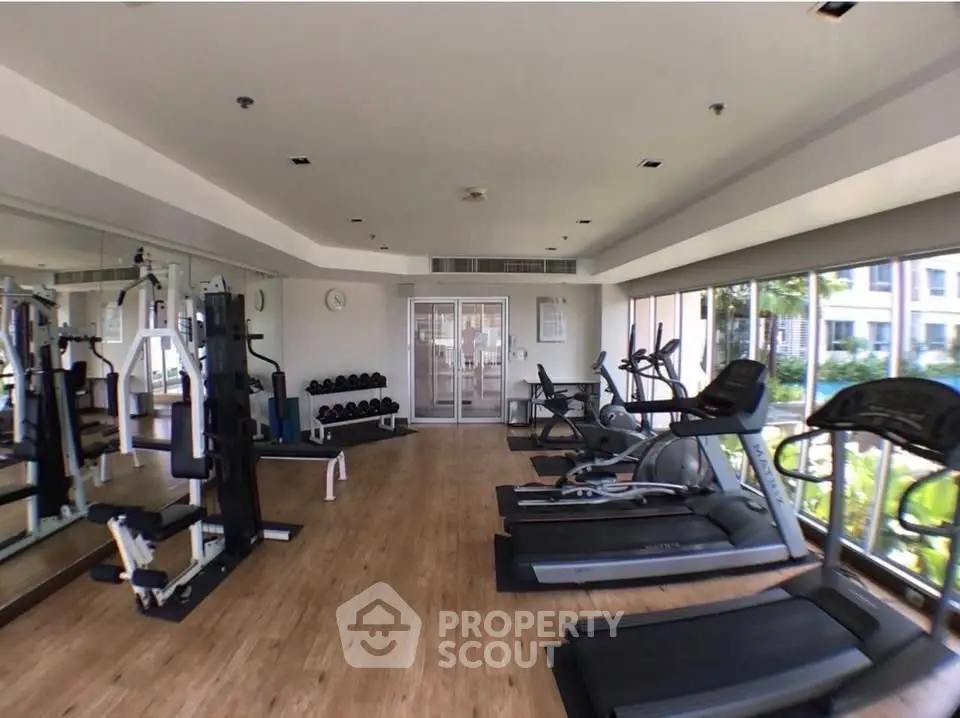 Spacious modern gym with state-of-the-art equipment and large windows offering natural light.