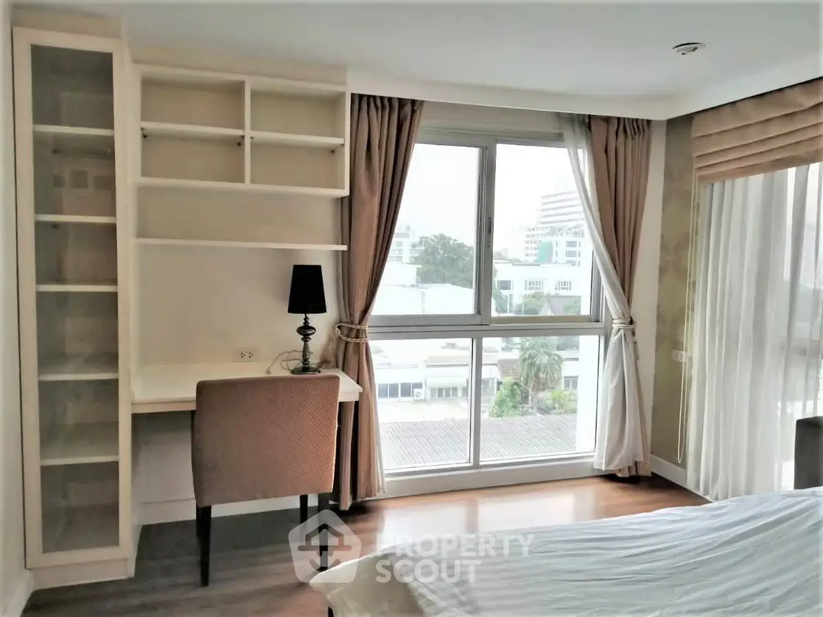 Bright bedroom with large window and built-in shelves in modern apartment