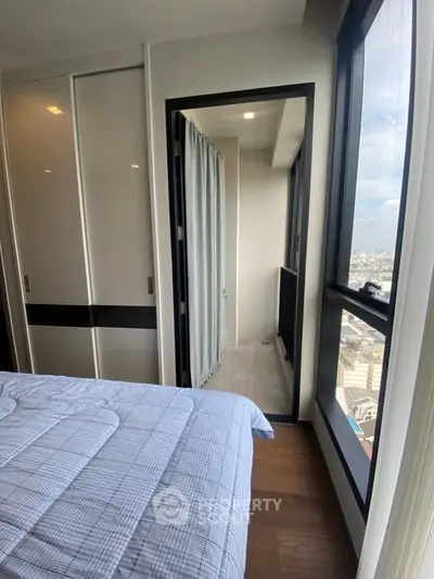 Modern bedroom with balcony access and city view, featuring sleek wardrobe and cozy bedding.