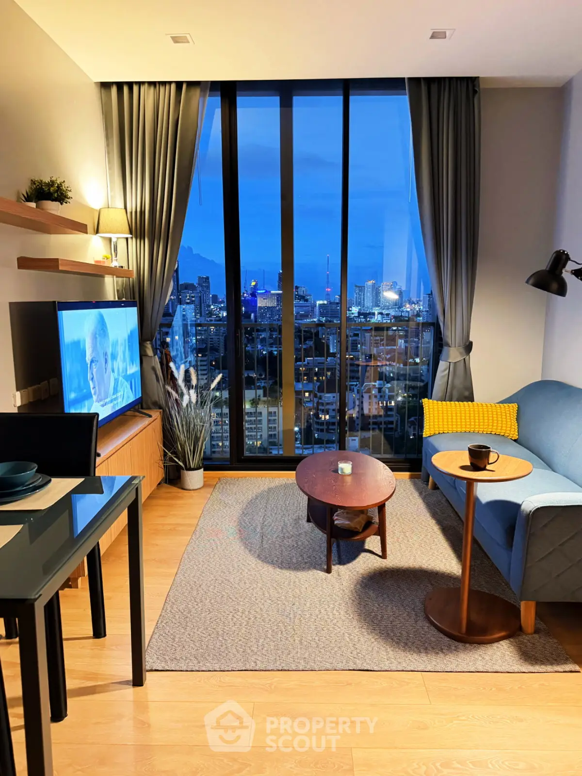 Modern living room with stunning city view, cozy seating, and elegant decor in a high-rise apartment.