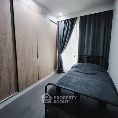 Cozy bedroom with dark curtains and wooden wardrobe, perfect for restful nights.