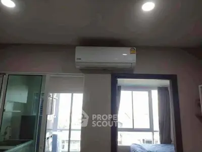 Modern apartment interior with air conditioning and large windows for natural light.