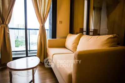 Cozy living room with a beige sofa and city view from large windows.