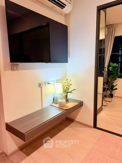 Modern living room with wall-mounted TV and stylish decor in a cozy apartment setting.