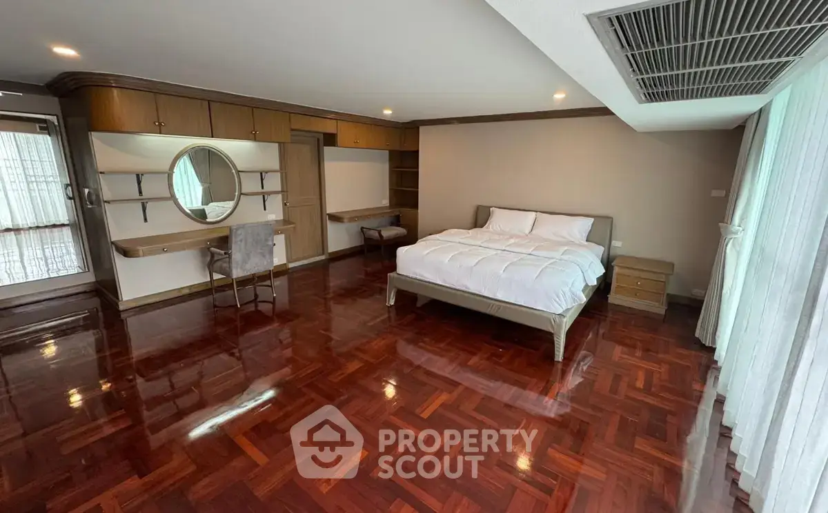 Spacious bedroom with elegant wooden flooring and modern furnishings