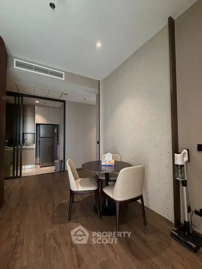 Modern dining area with elegant table and chairs, adjacent to a sleek kitchen with contemporary appliances.