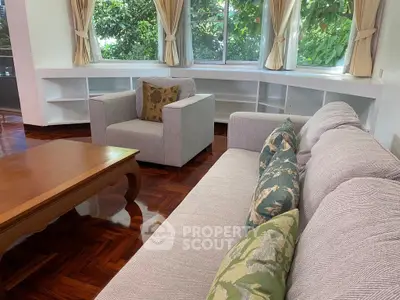 Spacious living room with elegant furniture and large windows offering lush garden views.