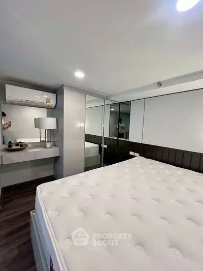 Modern bedroom with mirrored wardrobe and air conditioning unit