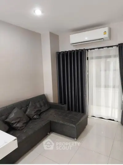 Modern living room with sleek black sofa and air conditioning