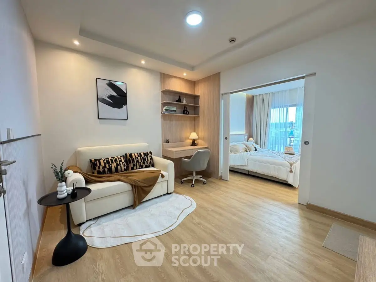 Modern living room with cozy seating and stylish decor leading to a bright bedroom.