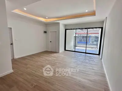 Spacious modern living room with wooden flooring and large window for natural light.