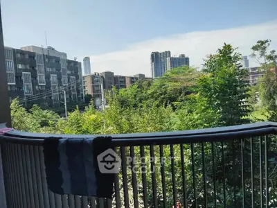 Scenic balcony view overlooking lush greenery and modern buildings in urban setting.