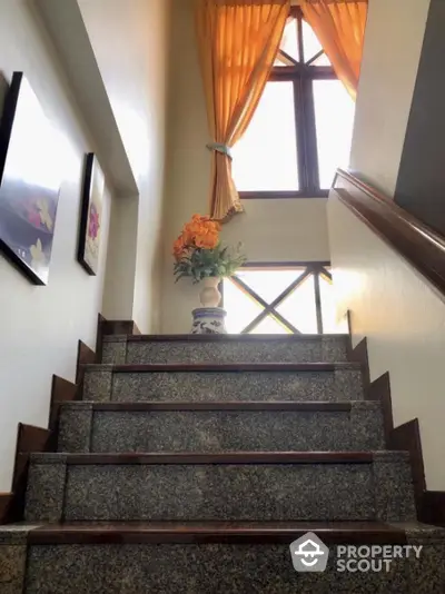 Elegant staircase with polished granite steps, natural light from window, and tasteful decor, enhancing the home's luxurious appeal.