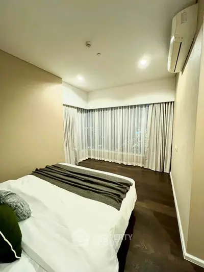 Modern bedroom with elegant decor and large windows in a stylish apartment.
