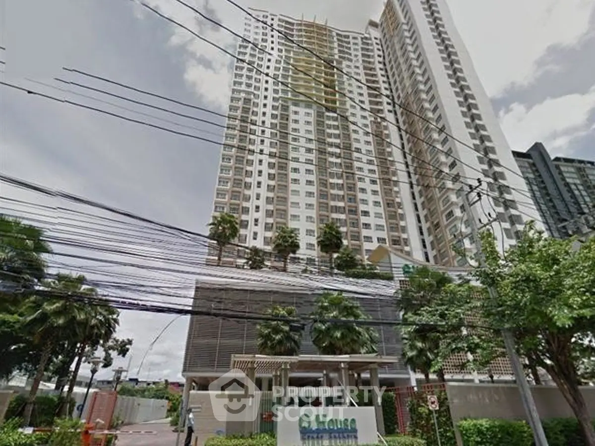 Modern high-rise condominium with lush greenery and urban skyline view.
