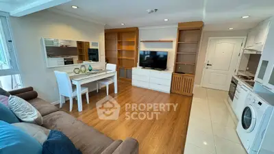 Spacious living room with modern furniture and open kitchen layout, featuring hardwood floors and ample natural light.
