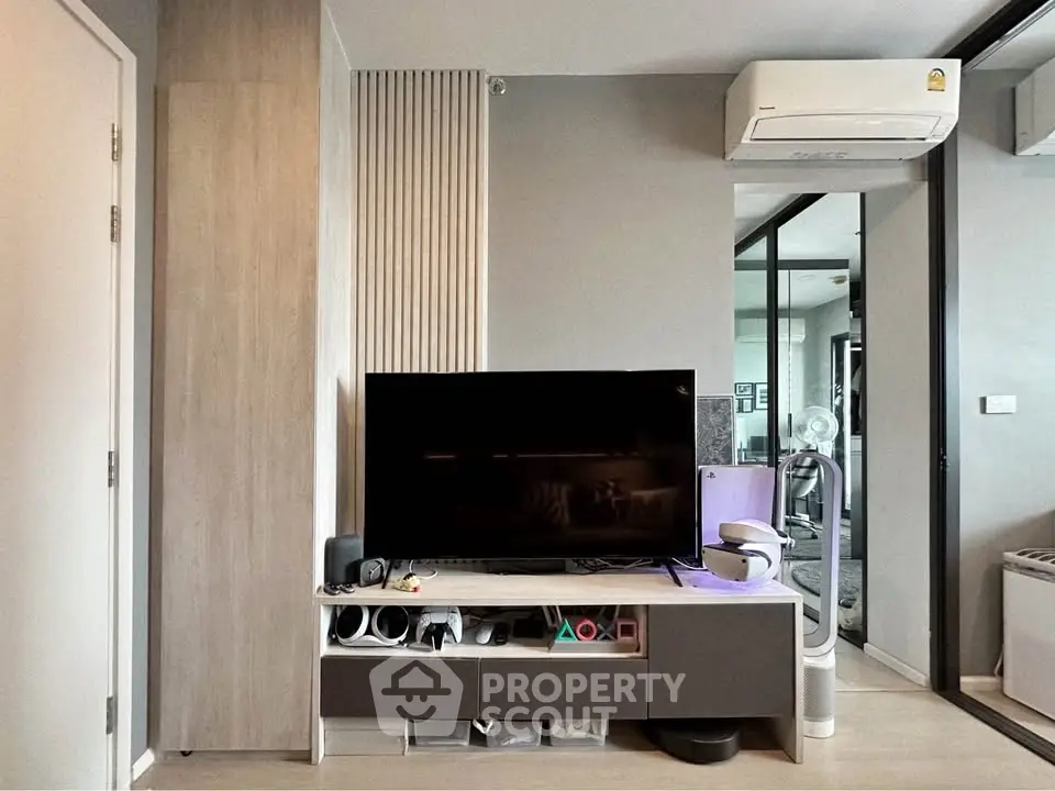 Modern living room with sleek TV setup and air conditioning in stylish apartment.