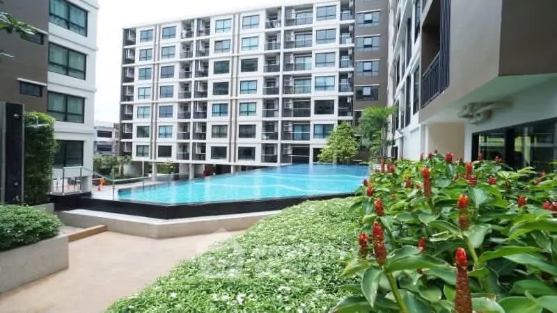 Modern condominium with a stunning pool and lush garden view, perfect for urban living.
