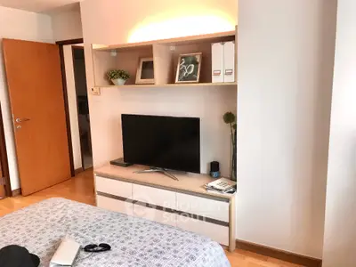 Cozy bedroom with modern TV setup and stylish shelving, perfect for relaxation and entertainment.
