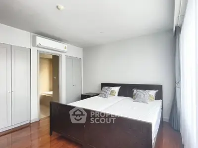 Spacious bedroom with wooden flooring and large windows in modern apartment