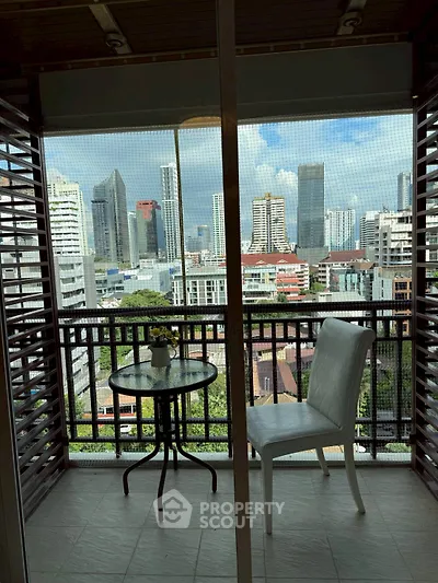 Stunning city view from a cozy balcony with seating area, perfect for relaxation.