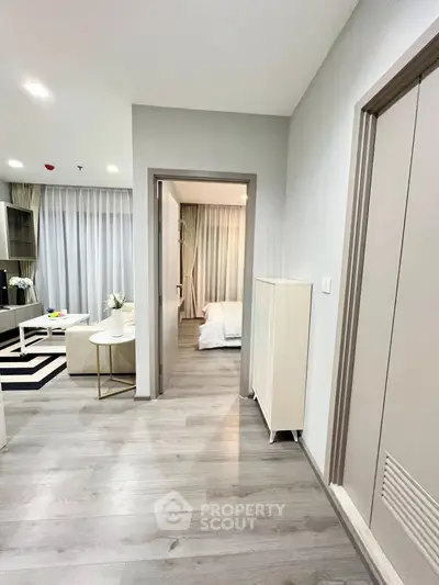 Modern apartment interior with open living room and bedroom view, featuring sleek flooring and contemporary decor.