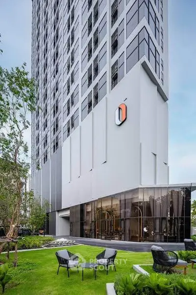 Modern high-rise building with lush garden and outdoor seating area