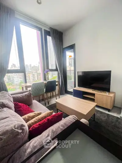Modern living room with city view, stylish furniture, and large windows in a high-rise apartment.
