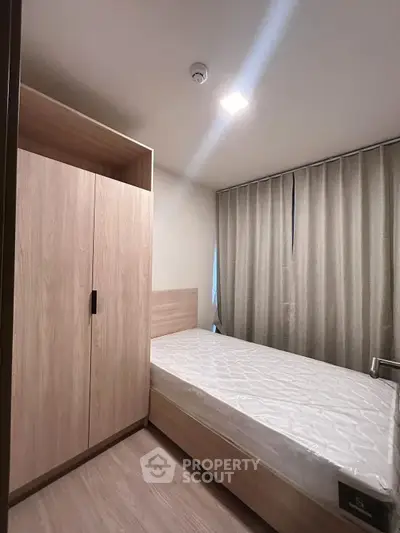 Modern bedroom with sleek wooden wardrobe and single bed, perfect for minimalist living.