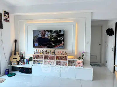 Modern living room with stylish TV setup and guitar, showcasing elegant decor and collectibles.