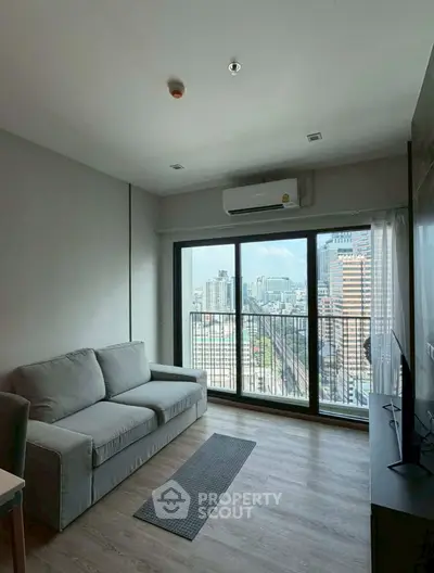 Modern living room with city view and large windows in high-rise apartment.
