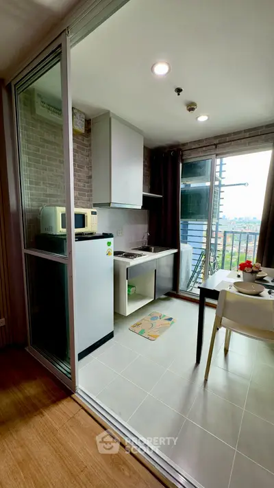 Modern compact kitchen with balcony view in urban apartment