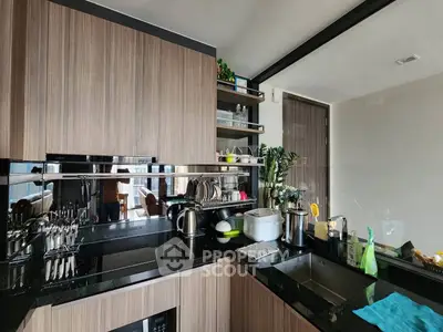 Modern kitchen with sleek cabinetry and black countertops, featuring a gas stove and open shelving.