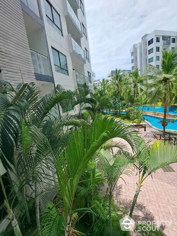 Modern apartment complex with lush greenery and inviting pool area.