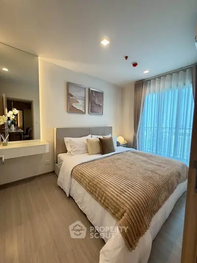 Modern bedroom with cozy decor and large window offering natural light.
