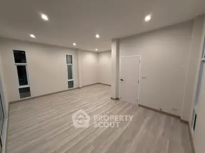 Spacious empty room with modern flooring and recessed lighting, ideal for customization.