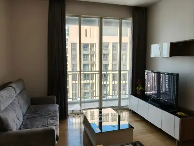 Modern living room with large windows and city view, featuring a cozy sofa and sleek TV unit.
