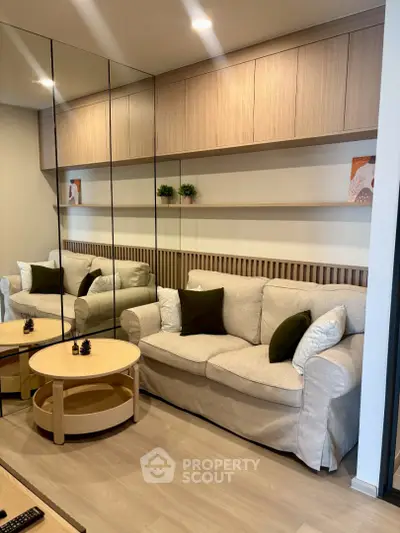 Modern living room with beige sofa, mirrored wall, and wooden shelves for a cozy ambiance.